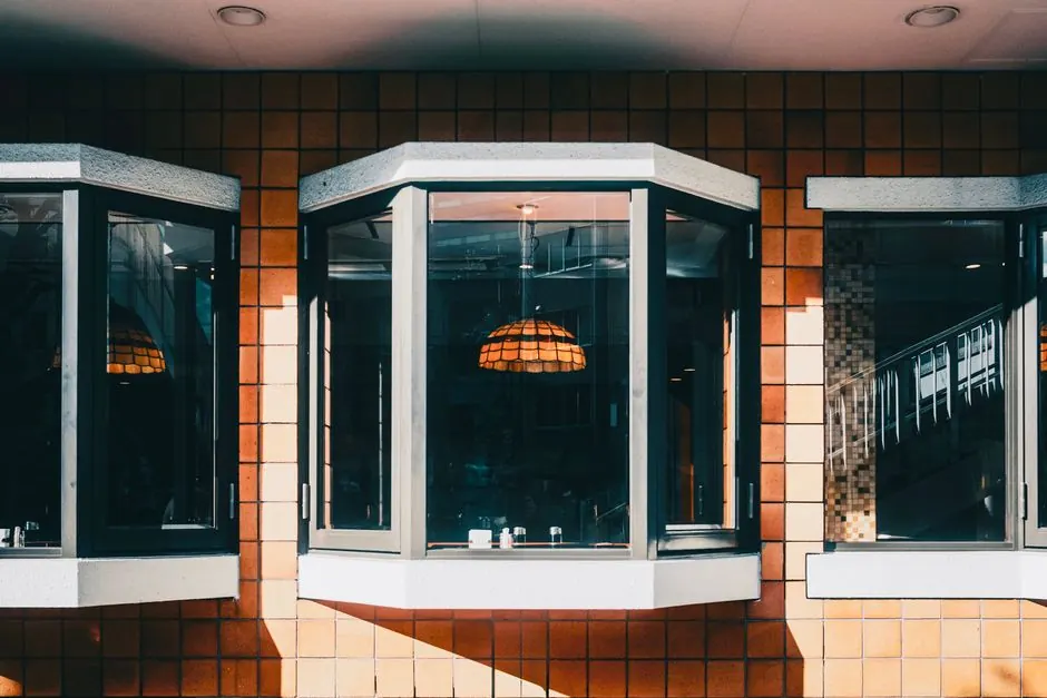 Modern bay windows with natural light and geometric brick pattern, featuring hanging lamp.